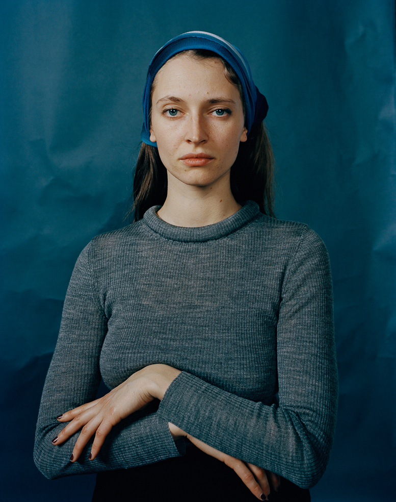 Junge Frau vor blauem Hintergrund, Arme verschränkt